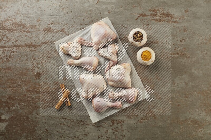 Mixed fresh chicken pieces on a parchment paper direct on a textured rustic background