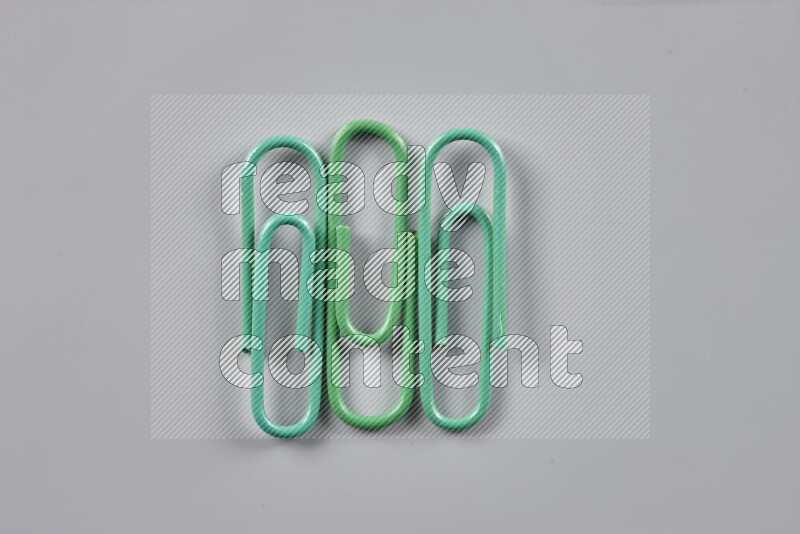 Green paper clips isolated on a grey background