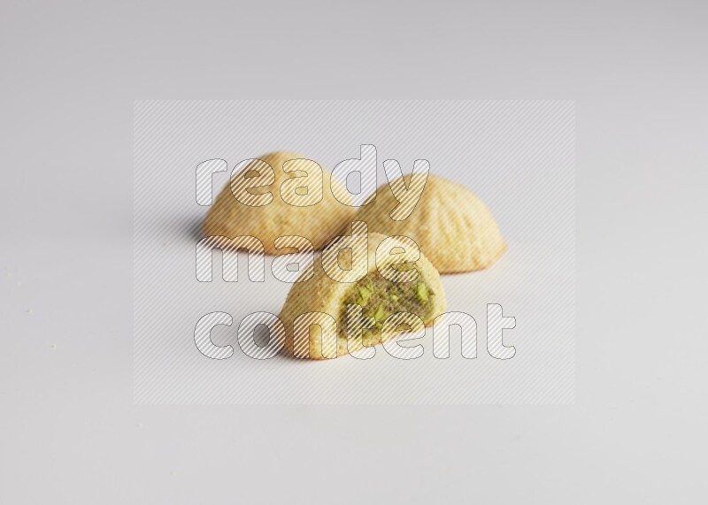 Three Pieces of Maamoul filled with pistachio paste  one of them is cut direct on white background