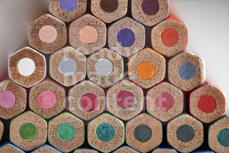 A close-up of the tips of colored pencils arranged in a bundle on white background