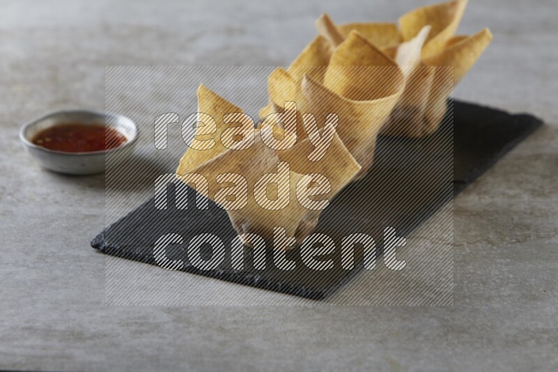 wonton cups with soy sauce ramkin on rectangle slate on grey textured counter top