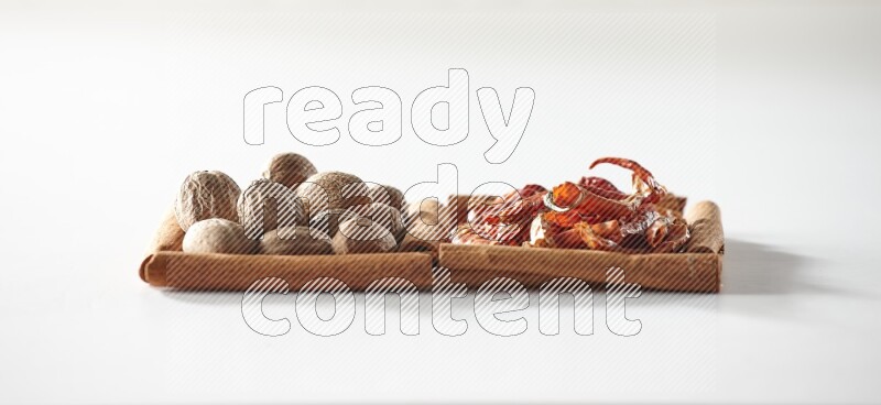 مربعان من أعواد القرفة ممتلئان بالفلفل الحار المجفف وجوزة الطيب علي خلفية بيضاء