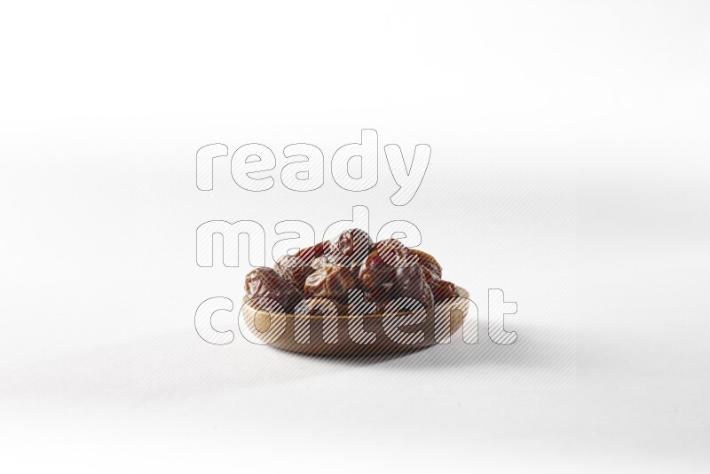 Dates in a wooden bowl on white background