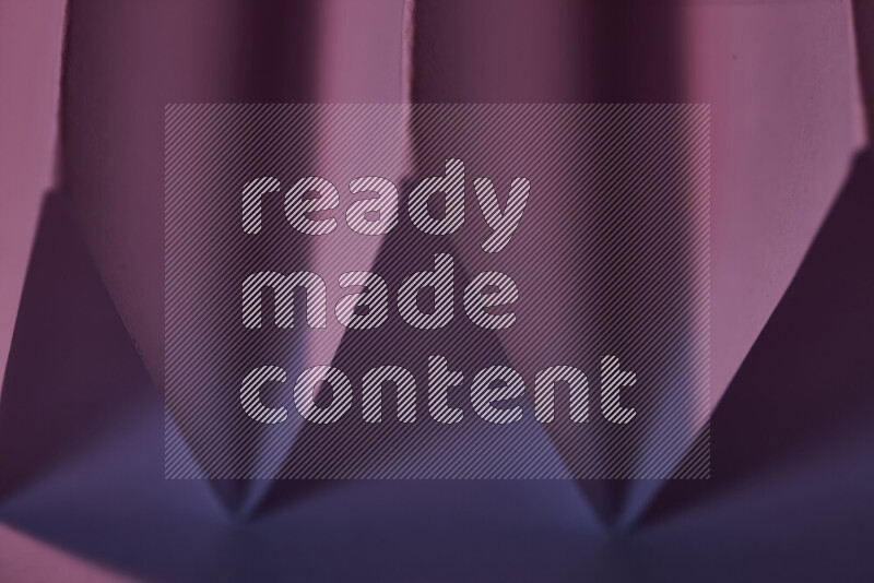 A close-up abstract image showing sharp geometric paper folds in purple gradients