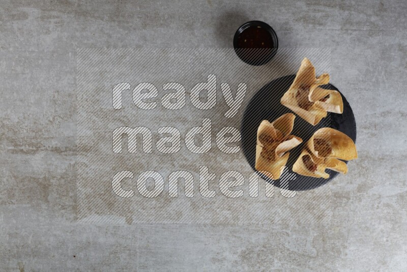 wonton cups with soy sauce ramkin on circle slate on grey textured counter top
