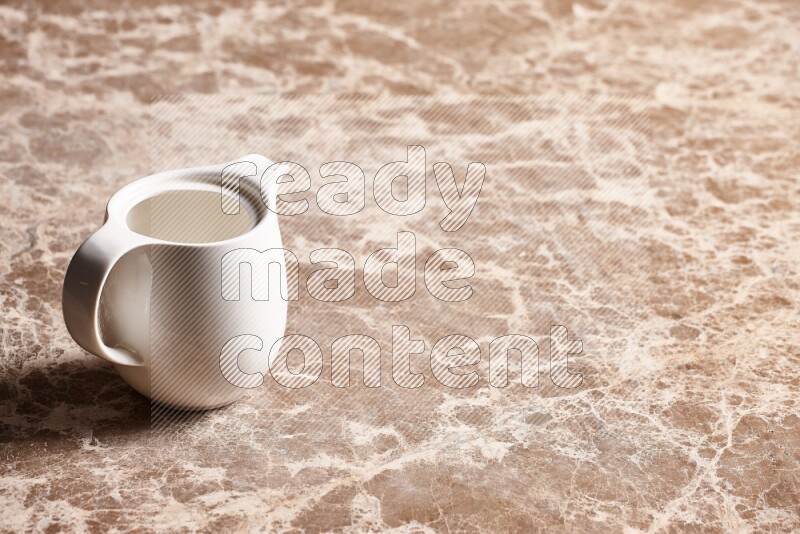 A ceramic milk jug on beige marble background