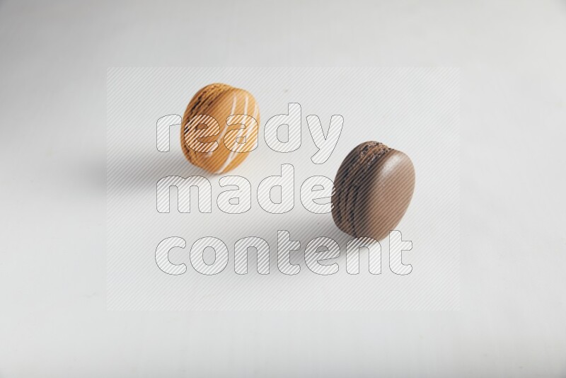 45º Shot of of two assorted Brown Irish Cream, and Brown Dark Chocolate macarons on white background