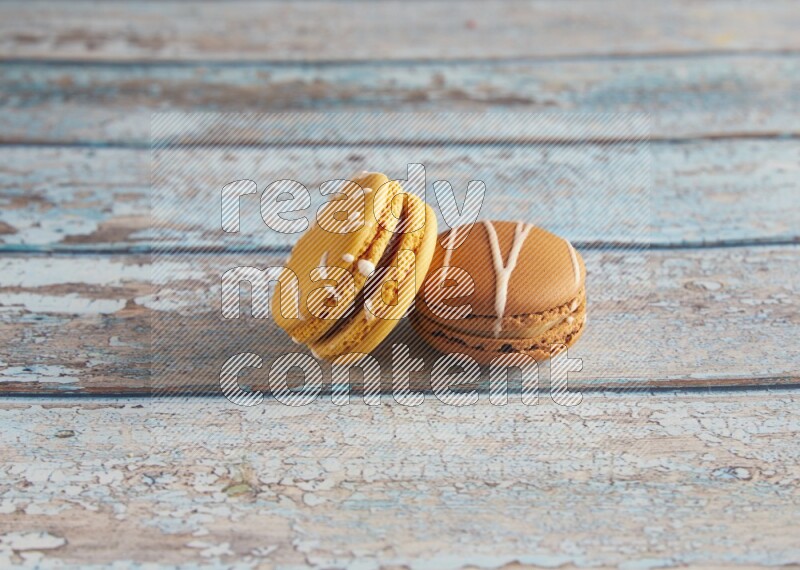 45º Shot of of two assorted Brown Irish Cream, and Yellow Piña Colada macarons on light blue background