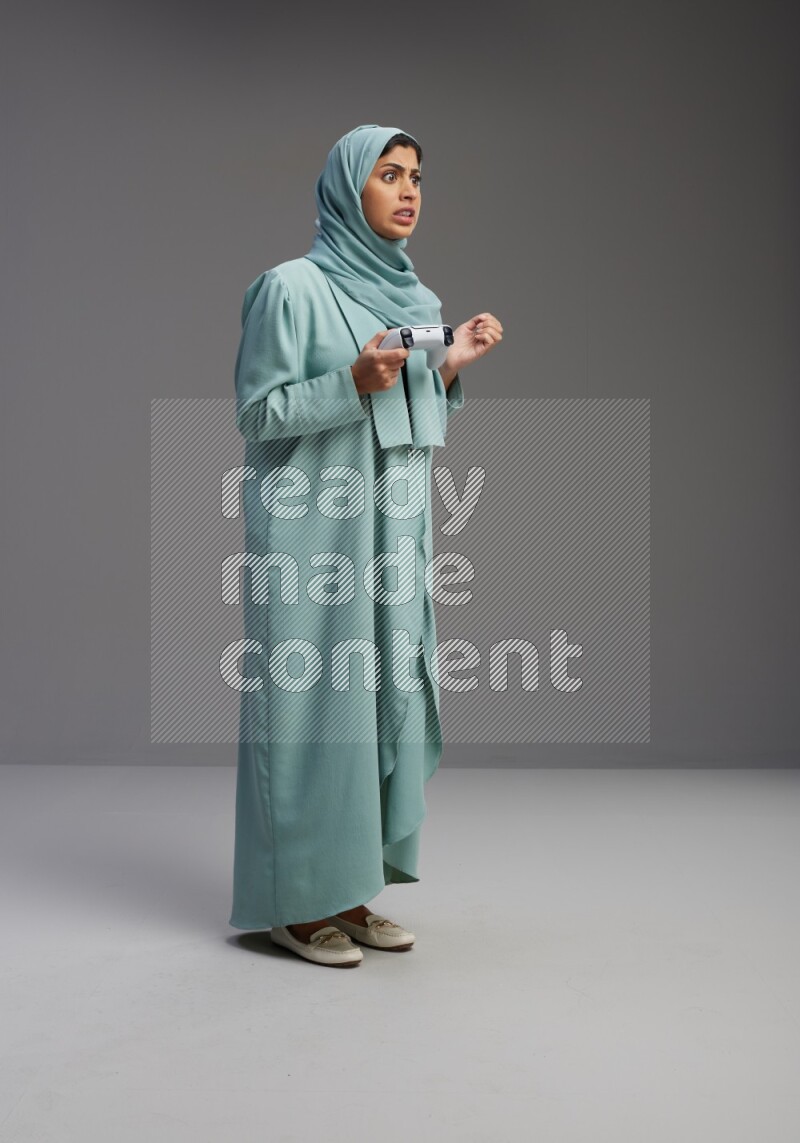 Saudi Woman wearing Abaya standing Playing Games on Gray background