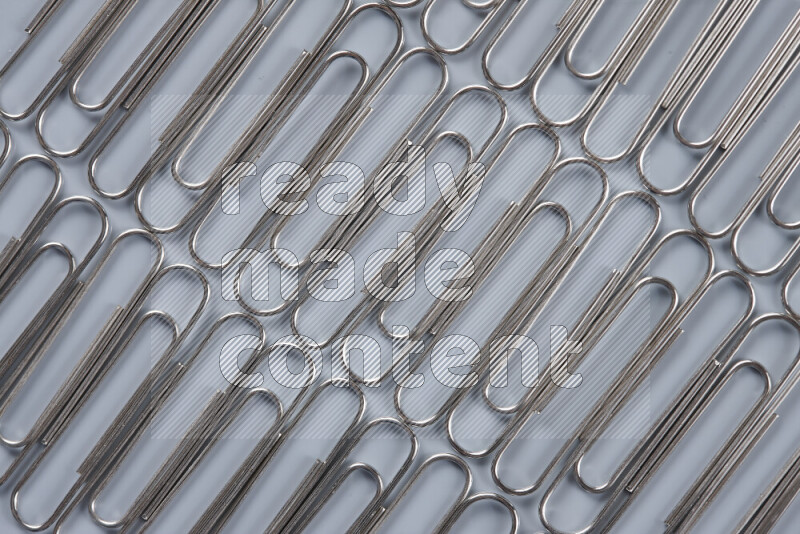 Silver paper clips isolated on a grey background