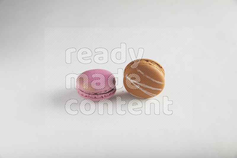 45º Shot of of two assorted Brown Irish Cream, and Purple Strawberry macarons on white background