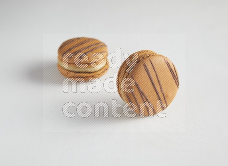 45º Shot of two light brown  Almond Cream macarons on white background