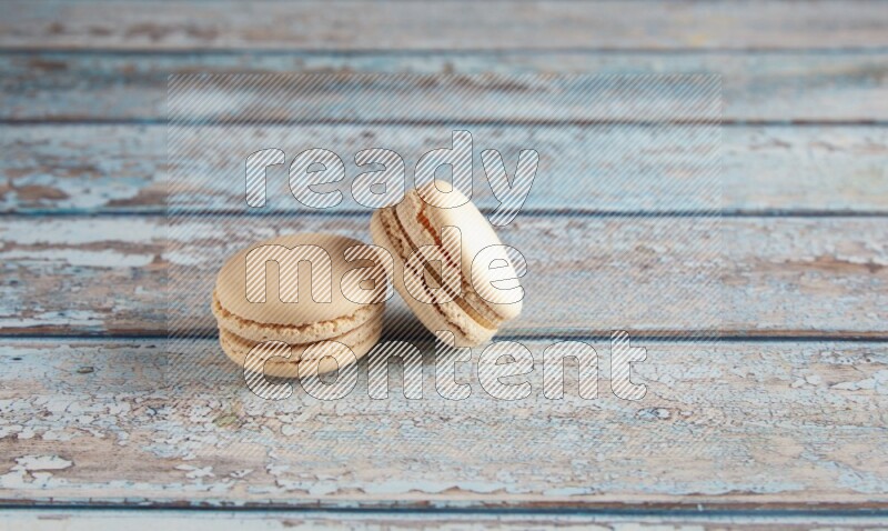 45º Shot of two White Caramel fleur de sel macarons on a light blue wooden background