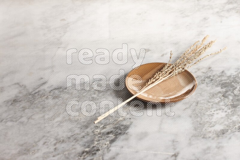 Wheat stalks on multicolored pottery plate on grey marble background