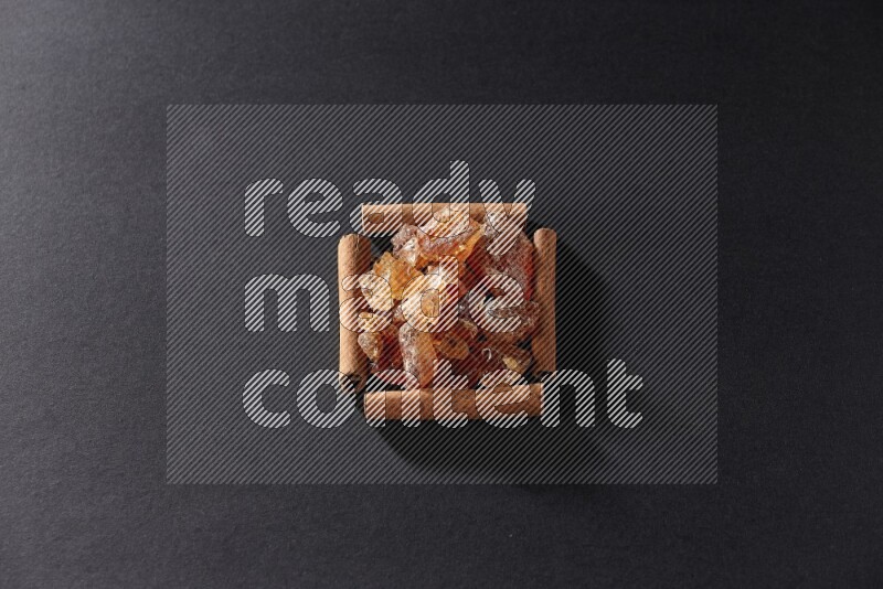A single square of cinnamon sticks full of Arabic gum on black flooring