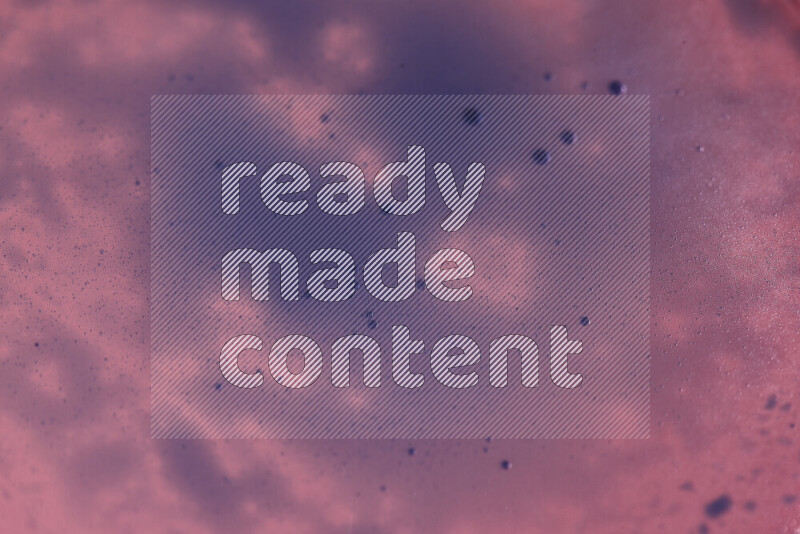 لقطات مقربة لقطرات ألوان مائية زرقاء على سطح الزيت على خلفية وردية