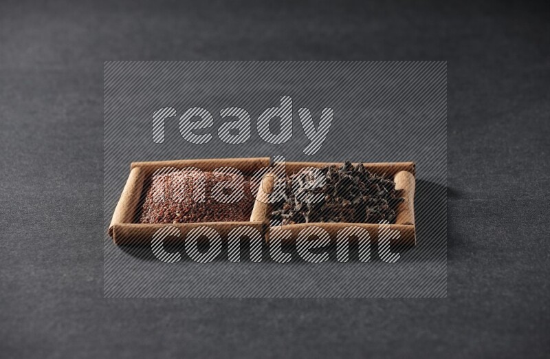 2 squares of cinnamon sticks full of garden cress and cloves on black flooring