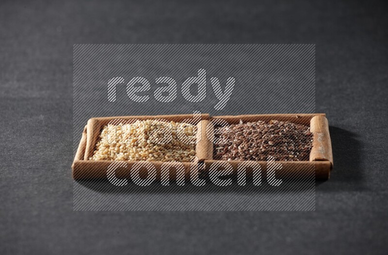 مربعان من أعواد القرفة ممتلئان ببذور الكتان وبذور السمسم علي خلفية سوداء