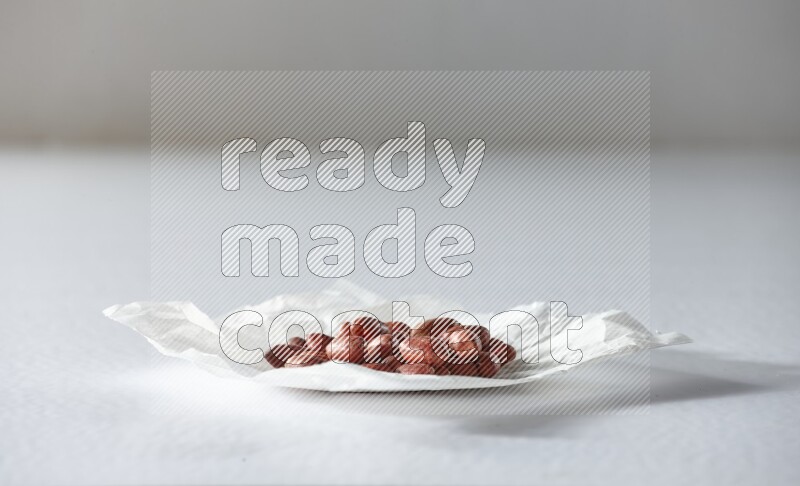 Red skin peanuts on a crumpled piece of paper on a white background in different angles