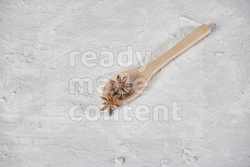 Star Anise in a wooden spoon on white flooring