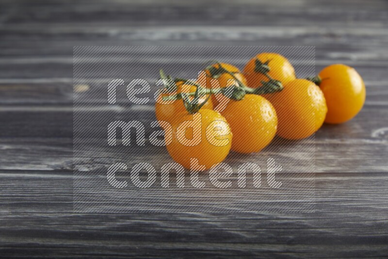 Yellow cherry tomato vein on a textured grey wooden background 45 degree