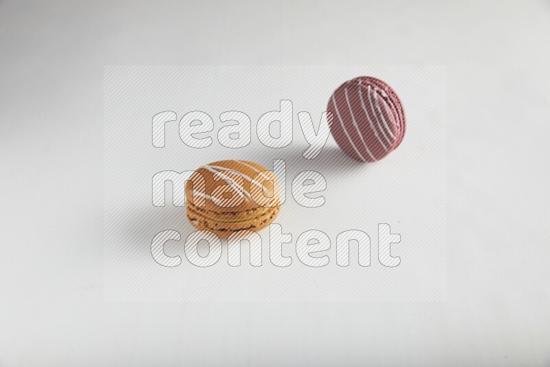 45º Shot of of two assorted Brown Irish Cream, and Red Poppy Flower macarons on white background