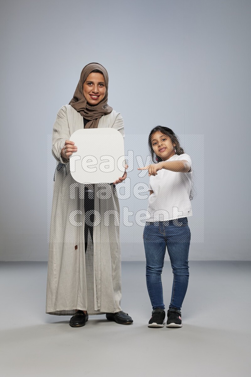 Mom and daughter standing holding social media sign on gray background