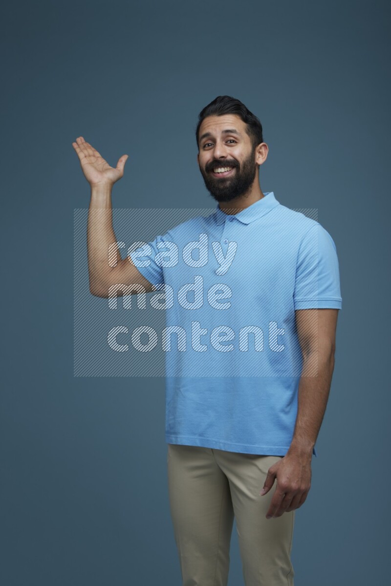 A man pointing  in a blue background wearing a Blue shirt