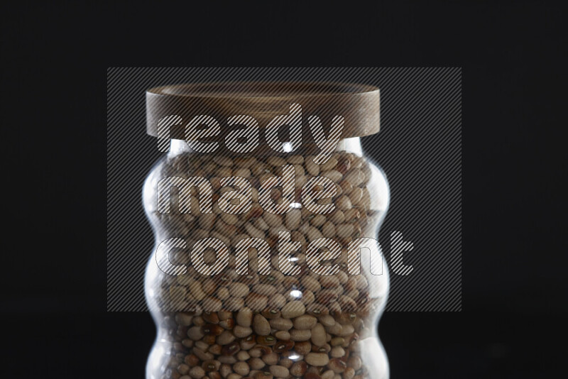Black-eyed peas in a glass jar on black background