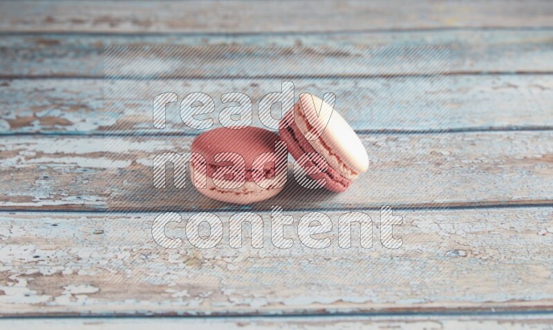 45º Shot of two Pink Litchi Raspberry macarons on light blue wooden background