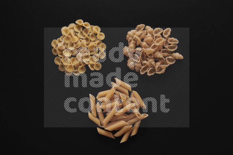 Different pasta types in bunches on black background
