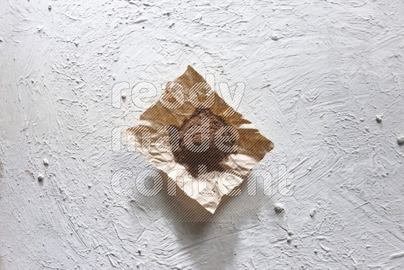 Cloves powder on crumpled piece of paper on a textured white flooring