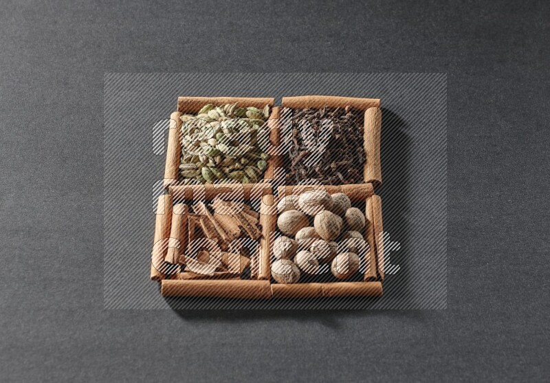 4 squares of cinnamon sticks full of cinnamon, cardamom, cloves and nutmegs on black flooring