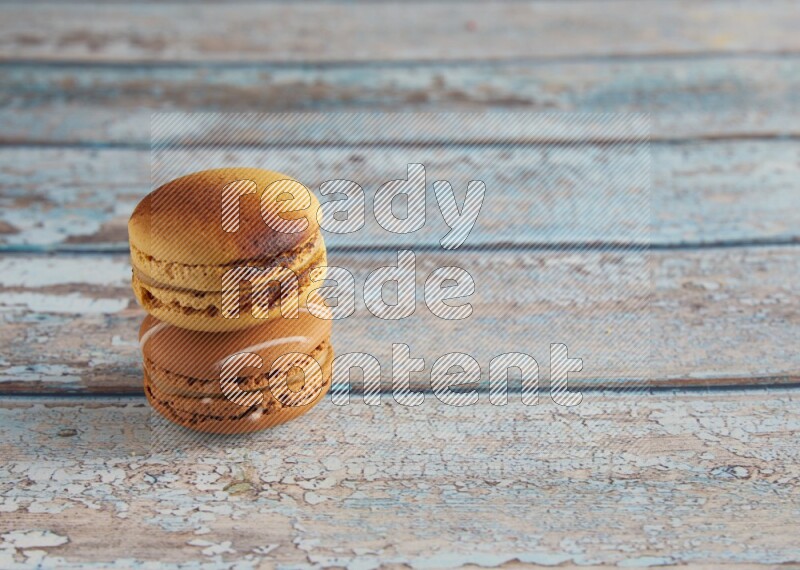 45º Shot of of two assorted Brown Irish Cream, and Yellow Crème Brulée macarons on light blue background