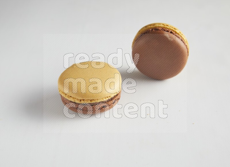 45º Shot of two Yellow and Brown Chai Latte macarons on white background