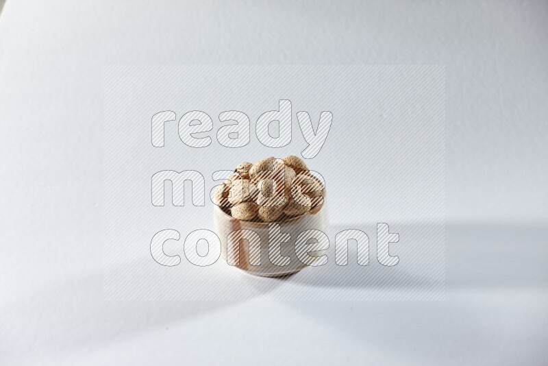 A beige ceramic bowl full of almonds on a white background in different angles