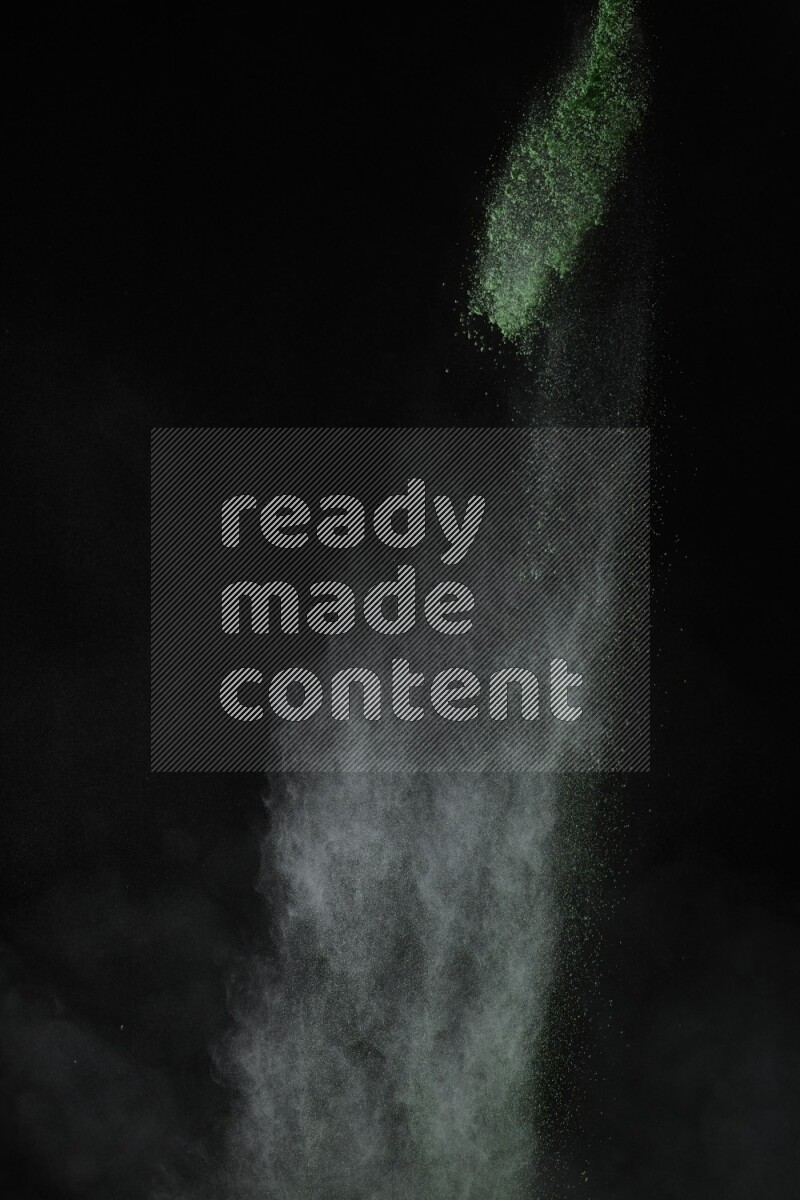 A side view of green powder explosion on black background