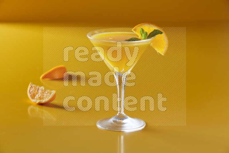 glass of orange juice with orange & mint  on yellow background