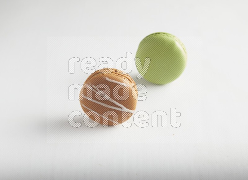 45º Shot of of two assorted Brown Irish Cream, and Green Pistachio macarons on white background