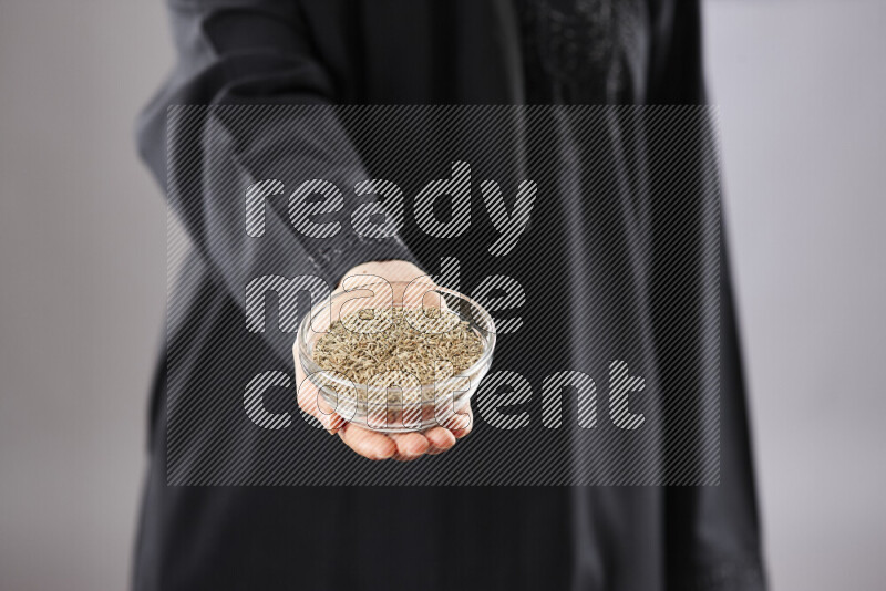 Woman in abaya holding different kinds of spices in different positions