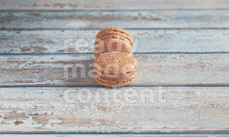 45º Shot of two Brown Hazelnuts macarons on light blue wooden background