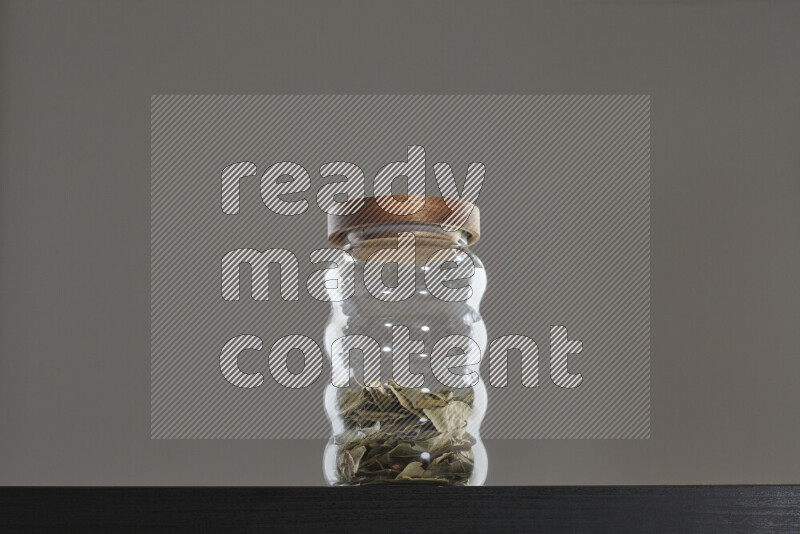 Bay laurel leaves in a glass jar on black background