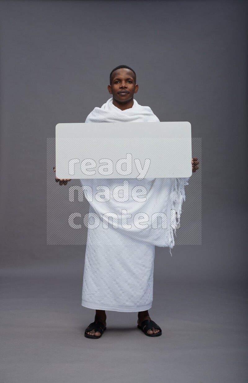 A man wearing Ehram Standing holding board sign on gray background
