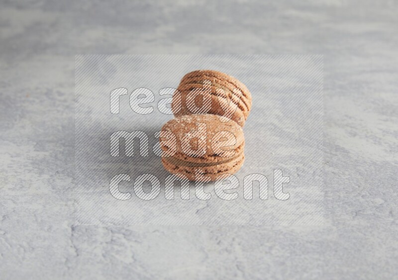 45º Shot of two Brown Hazelnuts macarons  on white  marble background