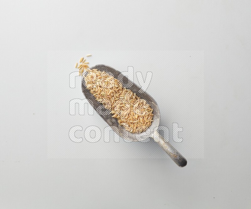 Top-view of a long grain brown rice, and shovel on white background