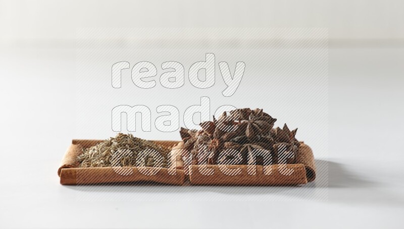 مربعان من أعواد القرفة ممتلئان باليانسون النجمي والكمون علي خلفية بيضاء