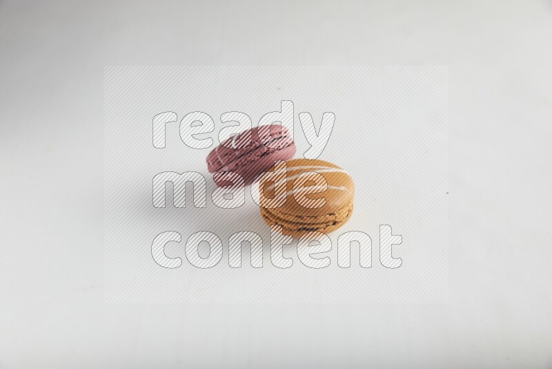 45º Shot of of two assorted Brown Irish Cream, and Red Poppy Flower macarons on white background