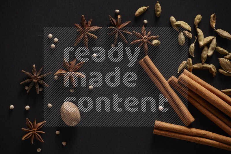 Cinnamon sticks, cardamom, star anise, nutmeg and white peppers on a black background
