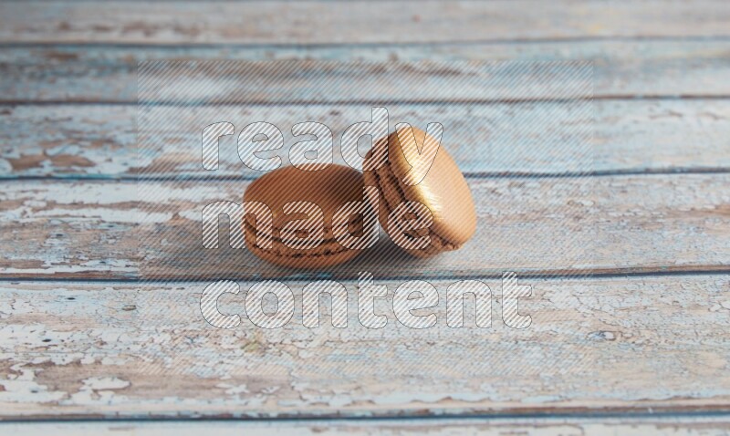 45º Shot of two Brown Coffee macarons on light blue wooden background