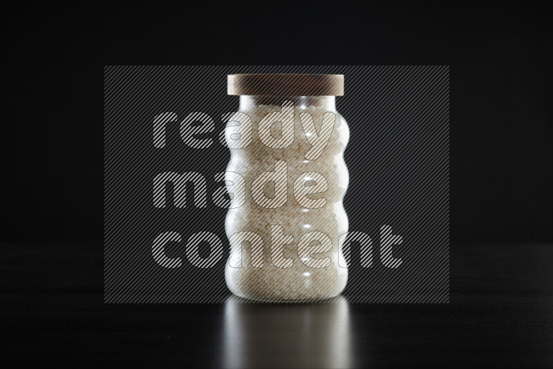 White rice in a glass jar on black background